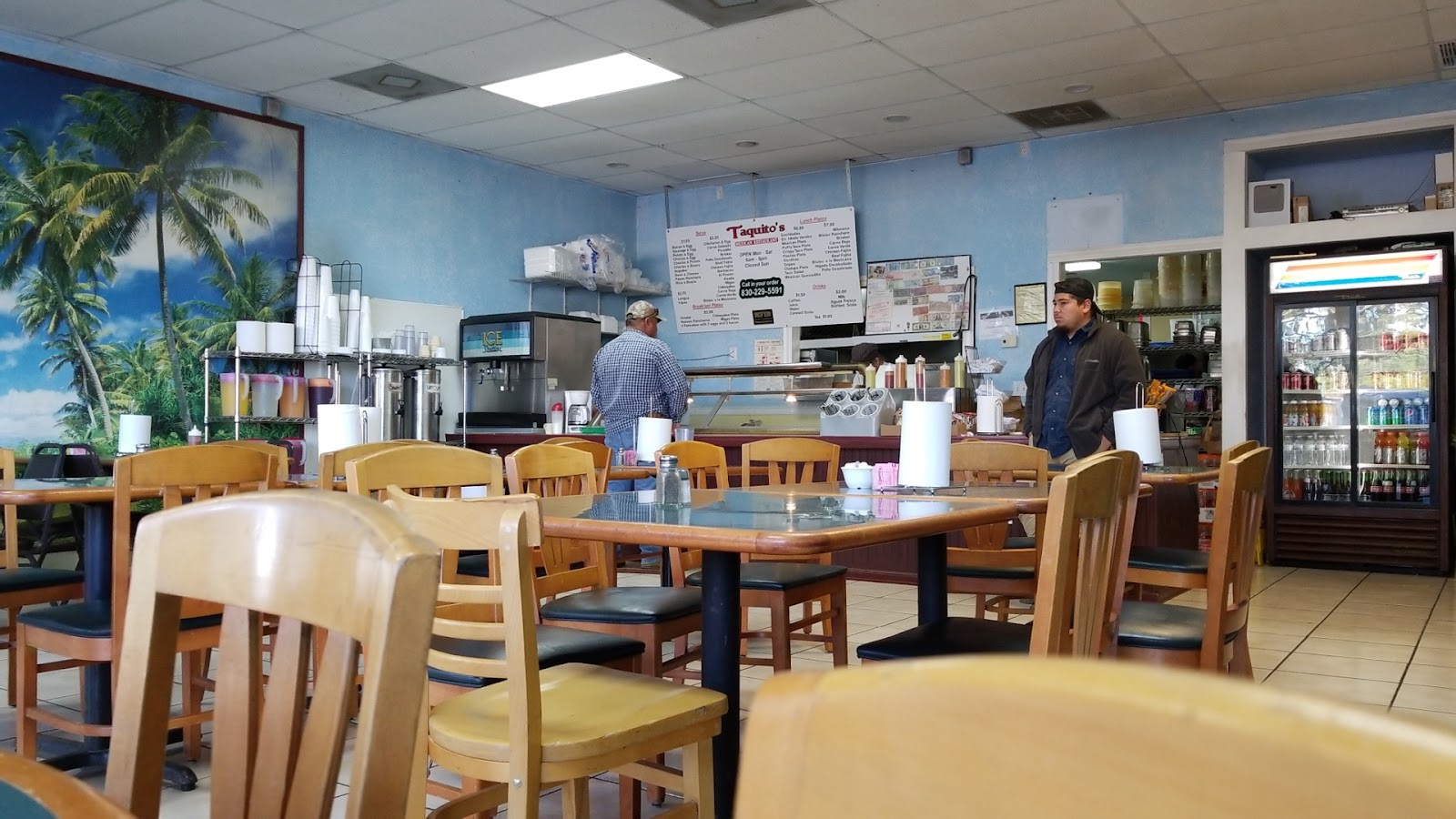 Bright dining room inside Taquito's Mexican Restaurant with tables and a beach mural